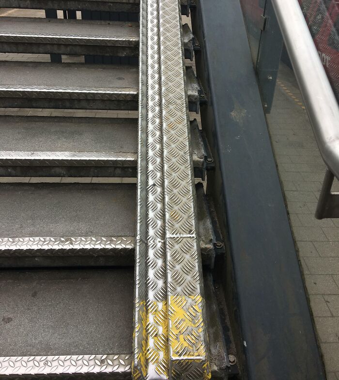 Schody s kovovým povrchom a protišmykovou úpravou na bezpečnú chôdzu, vedľa nich je zábradlie.