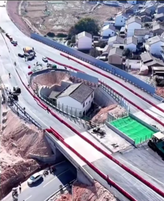 Výstavba obchádzky okolo domu uprostred cesty; pohľad zhora na cestný projekt v blízkosti obydlí.