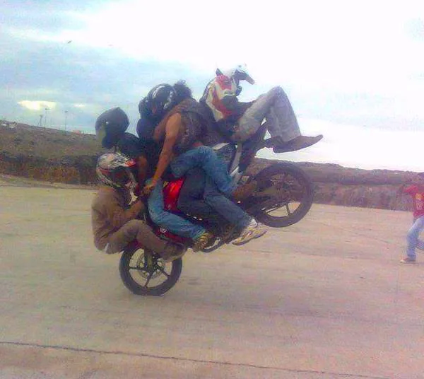 Motorkárska akrobacia: viac osôb na motocykli vykonáva kaskadérsky kúsok na jednom kolese.