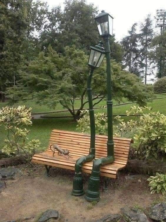 Lavička s kreatívnym dizajnom pouličných lámp namiesto nožičiek v parku.