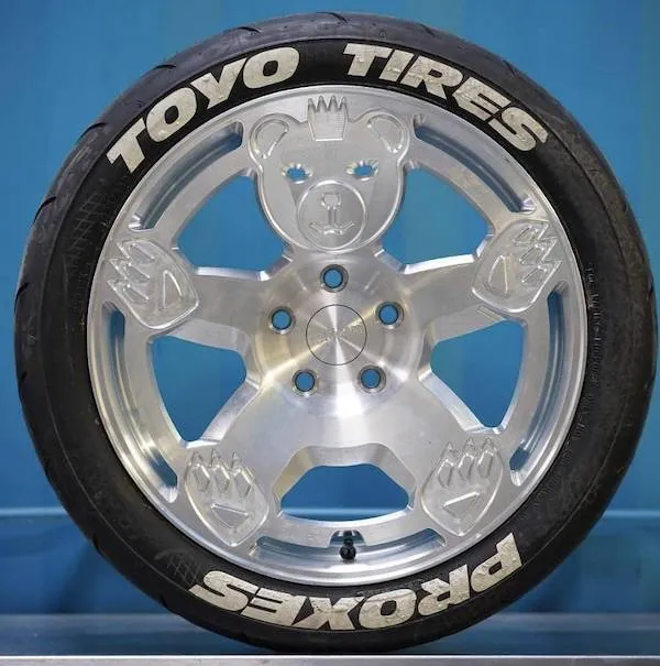 SUV koleso Toyo Tires s dizajnom medvedíka na hliníkovom disku, modré pozadie.