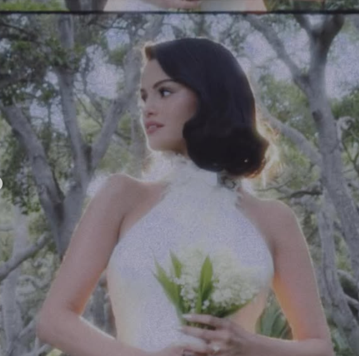 Osoba v bielych šatách drží kyticu, obklopená prírodou a slnečným svetlom.