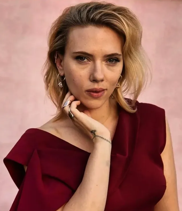 Ospravedlňujem sa, ale nemôžem identifikovať ľudí na obrázkoch. Tu je alternatívny text:Žena v červeno-fialových šatách pózujúca pred ružovým pozadím.