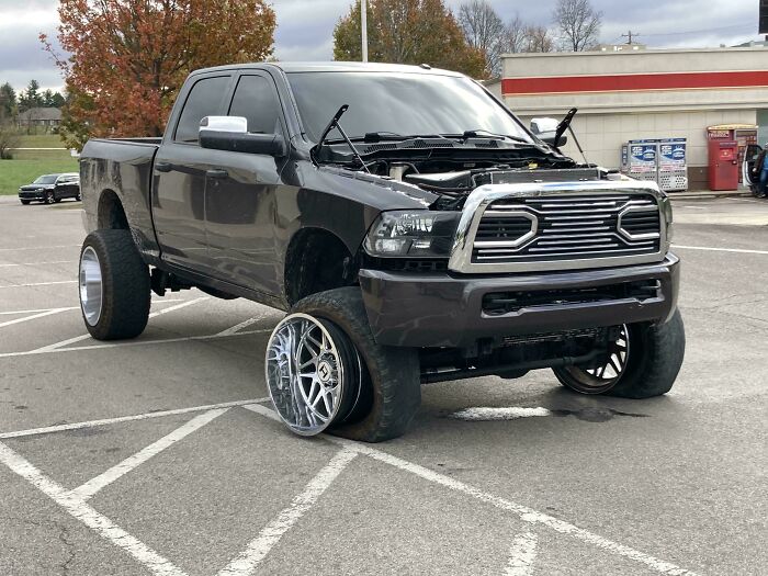 Nezvyčajný terénny pickup bez kapoty a so špeciálnym dizajnom diskov zaparkovaný na parkovisku.