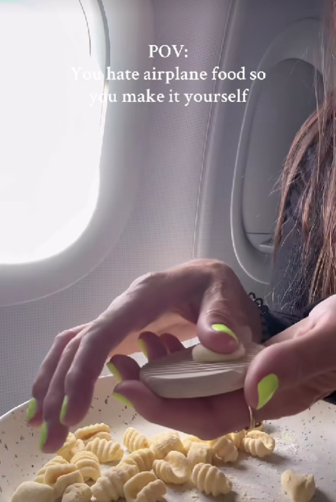 Osoba pripravuje čerstvé cestoviny vo vnútri lietadla, zatiaľ čo sedí pri okne.