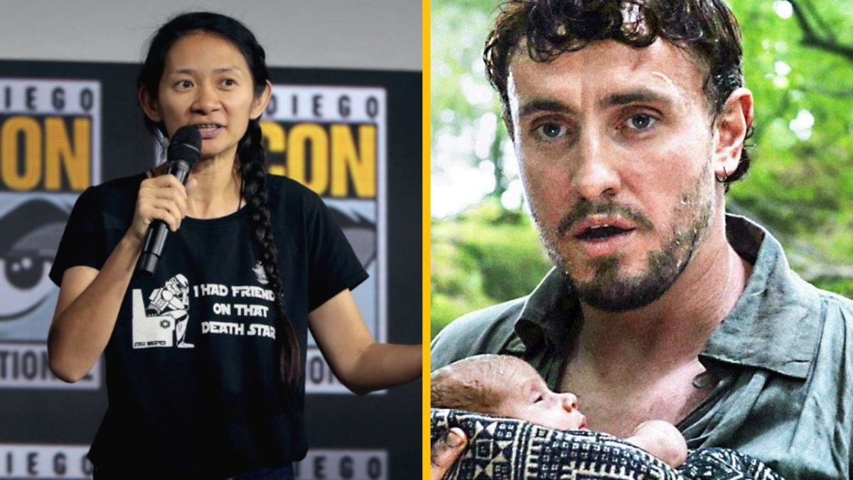 Osoba na pódiu s mikrofónom vedľa muža držiaceho dieťa v lese.