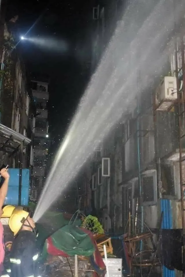 Hasiči v akcii večer hasia požiar v meste, striekajú vodu na budovu.