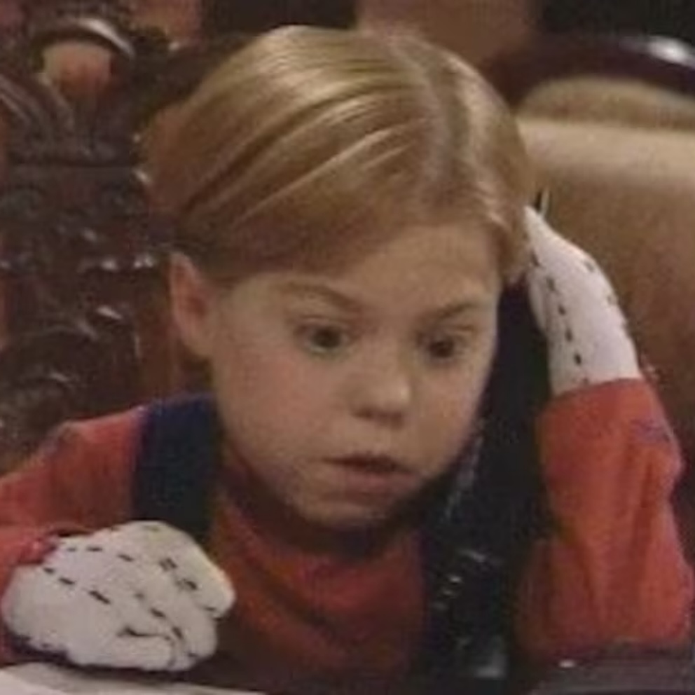 Chlapec s prekvapeným výrazom drží telefón a počúva. Má krátke svetlé vlasy a bielu rukavicu s čiernymi bodkami.