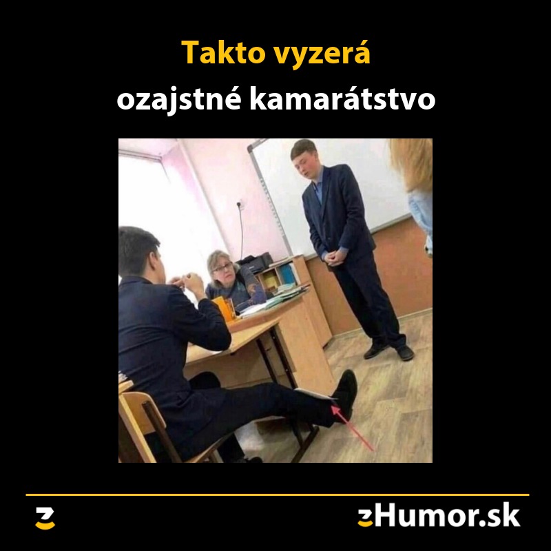 Študenti v triede, jeden stojí pred tabuľou, druhý mu nenápadne pomáha. Text: Takto vyzerá ozajstné kamarátstvo.