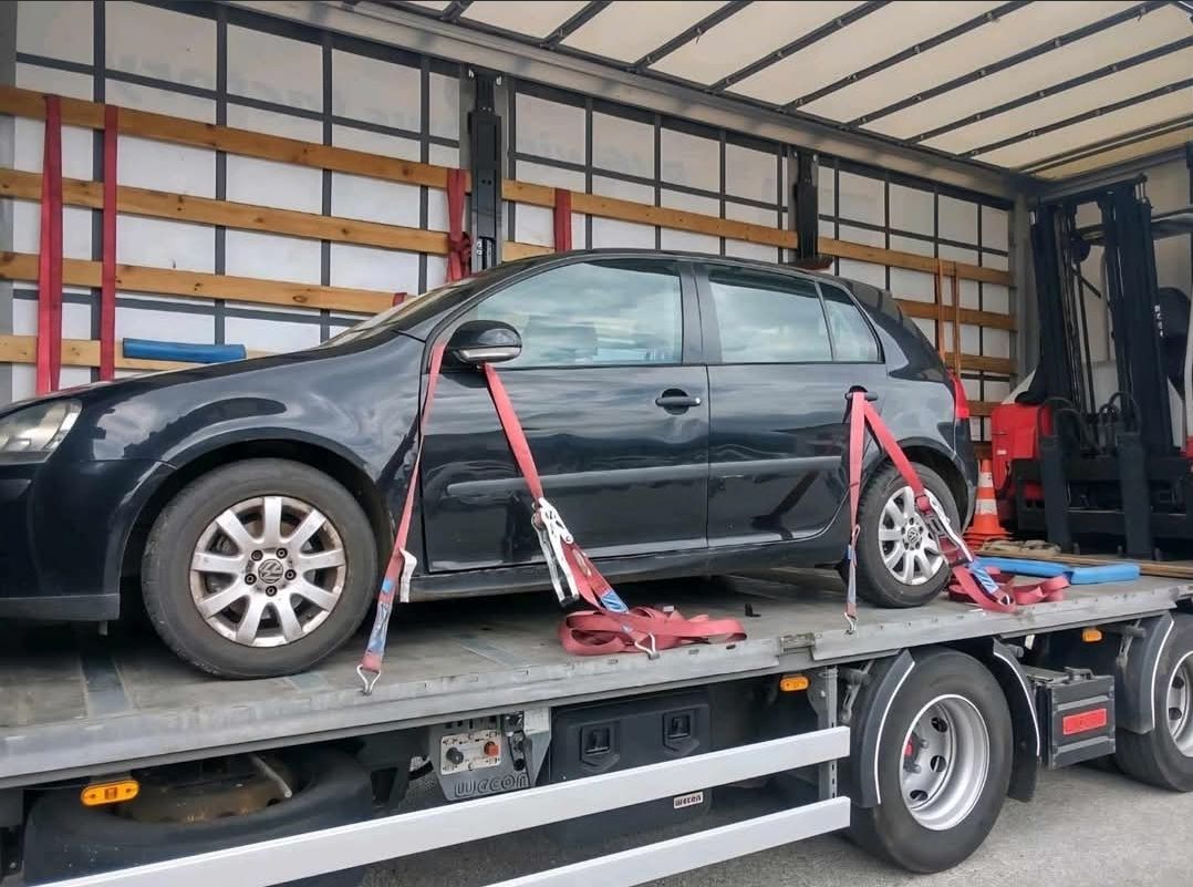 Auto bezpečne upevnené popruhmi na nákladnom vozidle v uzavretom priestore.