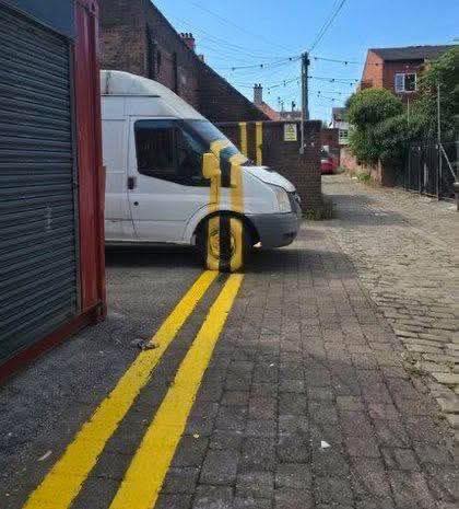 Dodávka na úzkej uličke s optickou ilúziou pomocou žltých čiar na stĺpe a zemi.