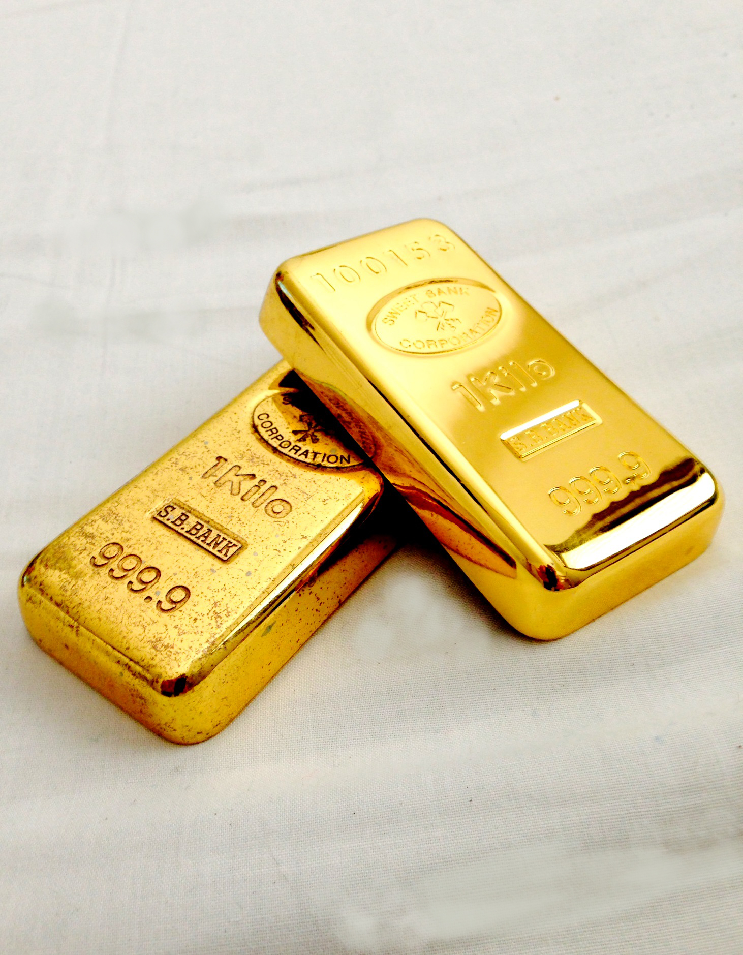 Dve zlaté tehličky s rýdzosťou 999,9 na bielej podložke, symbol bohatstva a investície.