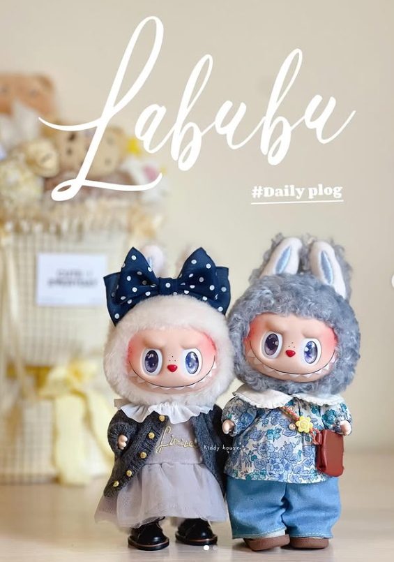 Dve roztomilé bábiky v originálnych outfitoch stoja spolu pred dekoratívnym pozadím s nápisom Labubu.