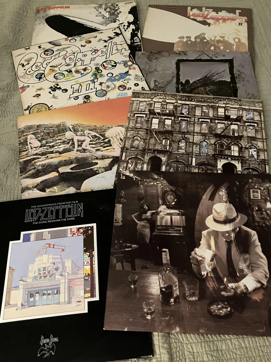 Zbierka historických vinylov rockovej kapely na posteli, obaly s rôznymi výtvarnými motívmi.