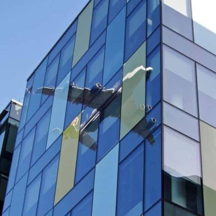 Odraz lietadla na sklenenej fasáde moderného kancelárskeho komplexu pod modrou oblohou.