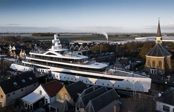 Jachta prechádza úzkou holandskou dedinou s kostolom v pozadí.