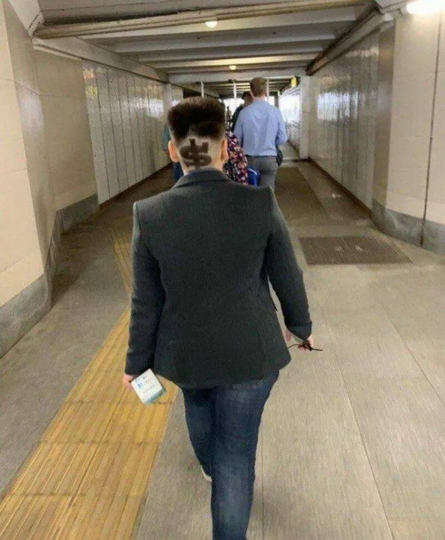 Osoba kráča chodbou s originálnym účesom so vzorom na zátylku.