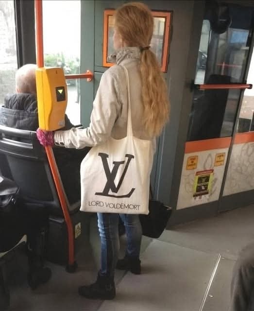 Žena v autobuse s taškou Lord Voldemort s dizajnom pripomínajúcim logo luxusnej značky.