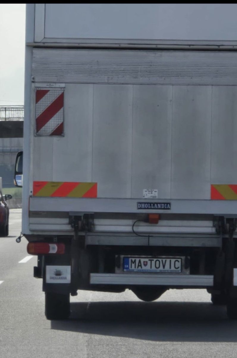 Nákladné auto na ceste s poznávacou značkou MA TOVIC, vzadu červené pruhy a nápis Dhollandia.