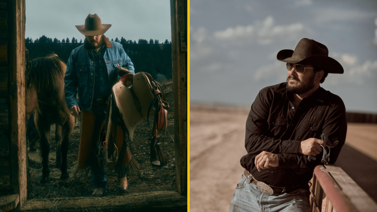 Kovboj s čiernym klobúkom vedľa koňa, drží sedlo, pózuje v prírode a opiera sa o oplotenie na ranči.