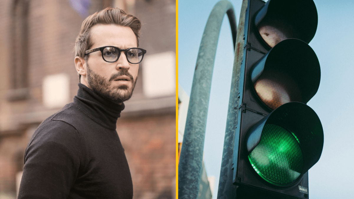 Muž v čiernom roláku vedľa svietiaceho zeleného semaforu.