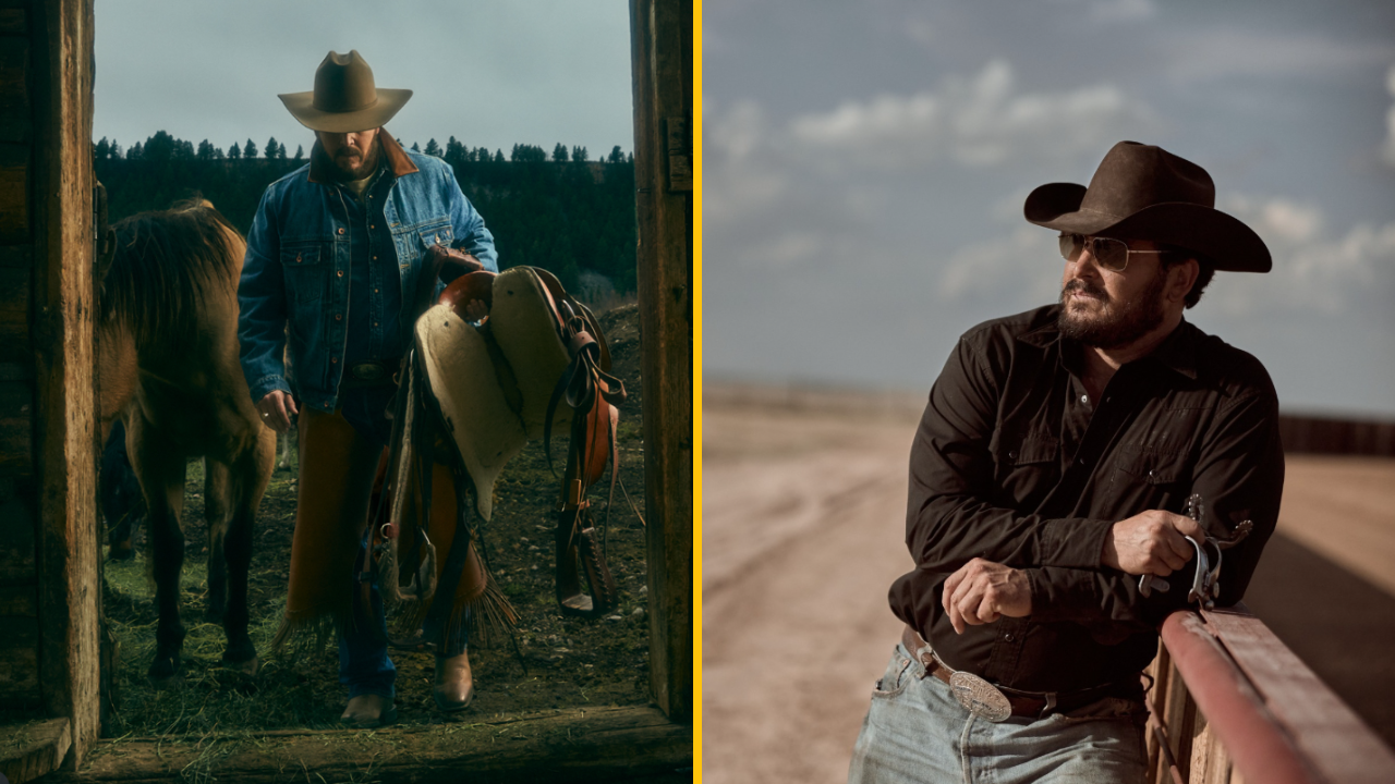 Kovboj s čiernym klobúkom vedľa koňa, drží sedlo, pózuje v prírode a opiera sa o oplotenie na ranči.