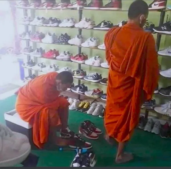 Mnísi v oranžových rúchach skúšajú tenisky v obchode s topánkami.