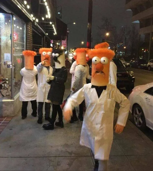 Ľudia v kostýmoch s oranžovými hlavami na večernej mestách ulici, oblečení v bielych plášťoch.