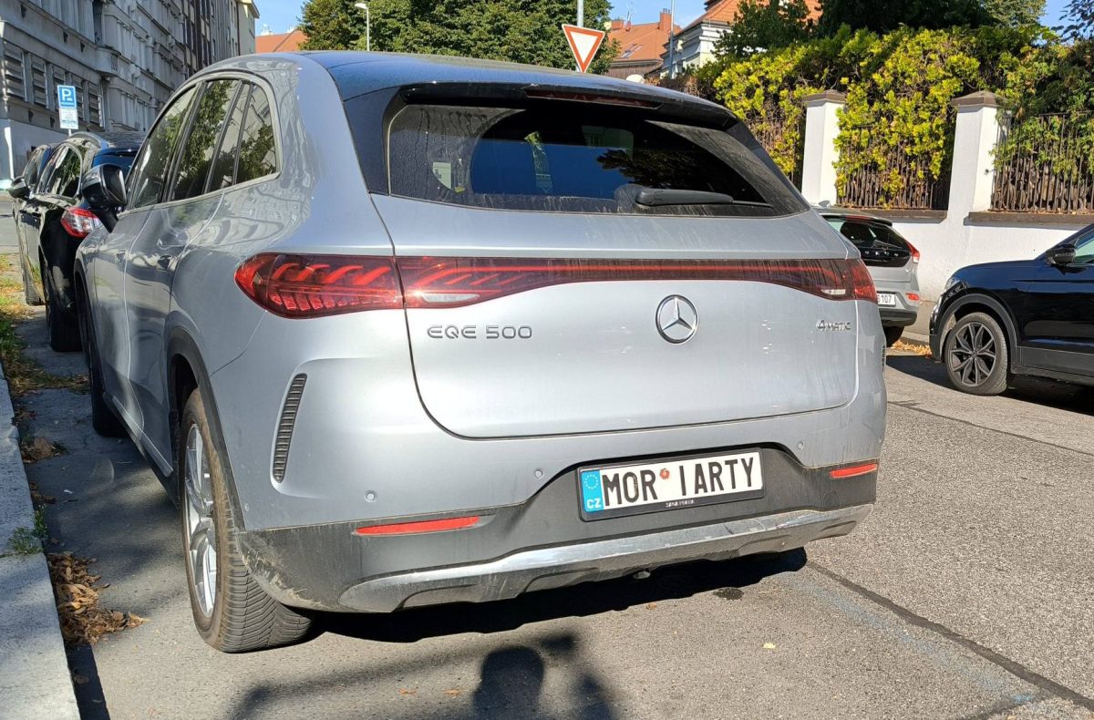 Strieborný Mercedes EQE 500, zaparkovaný na ulici v mestskej oblasti.