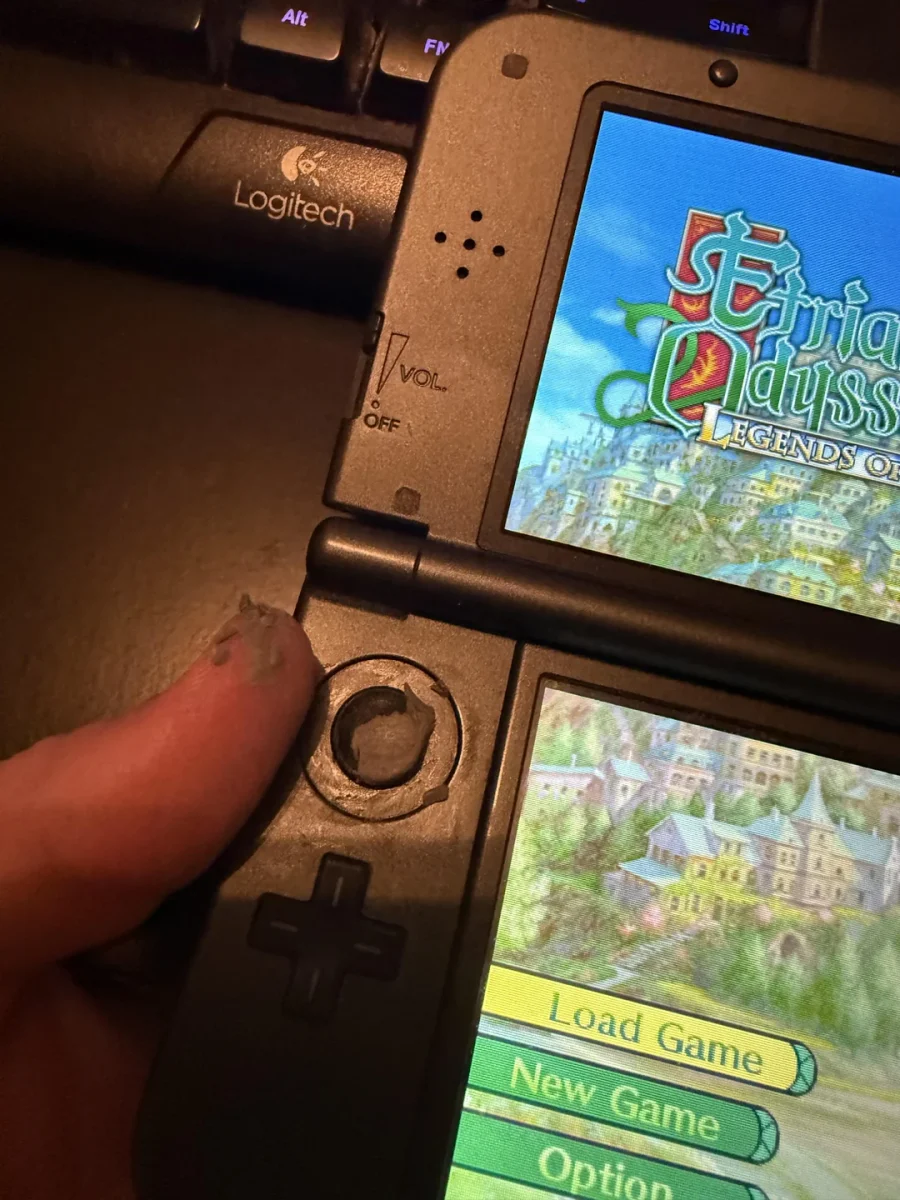 Nintendo 3DS displej s hrou Etrian Odyssey, detail na poničený ovládač, klávesnica Logitech v pozadí.