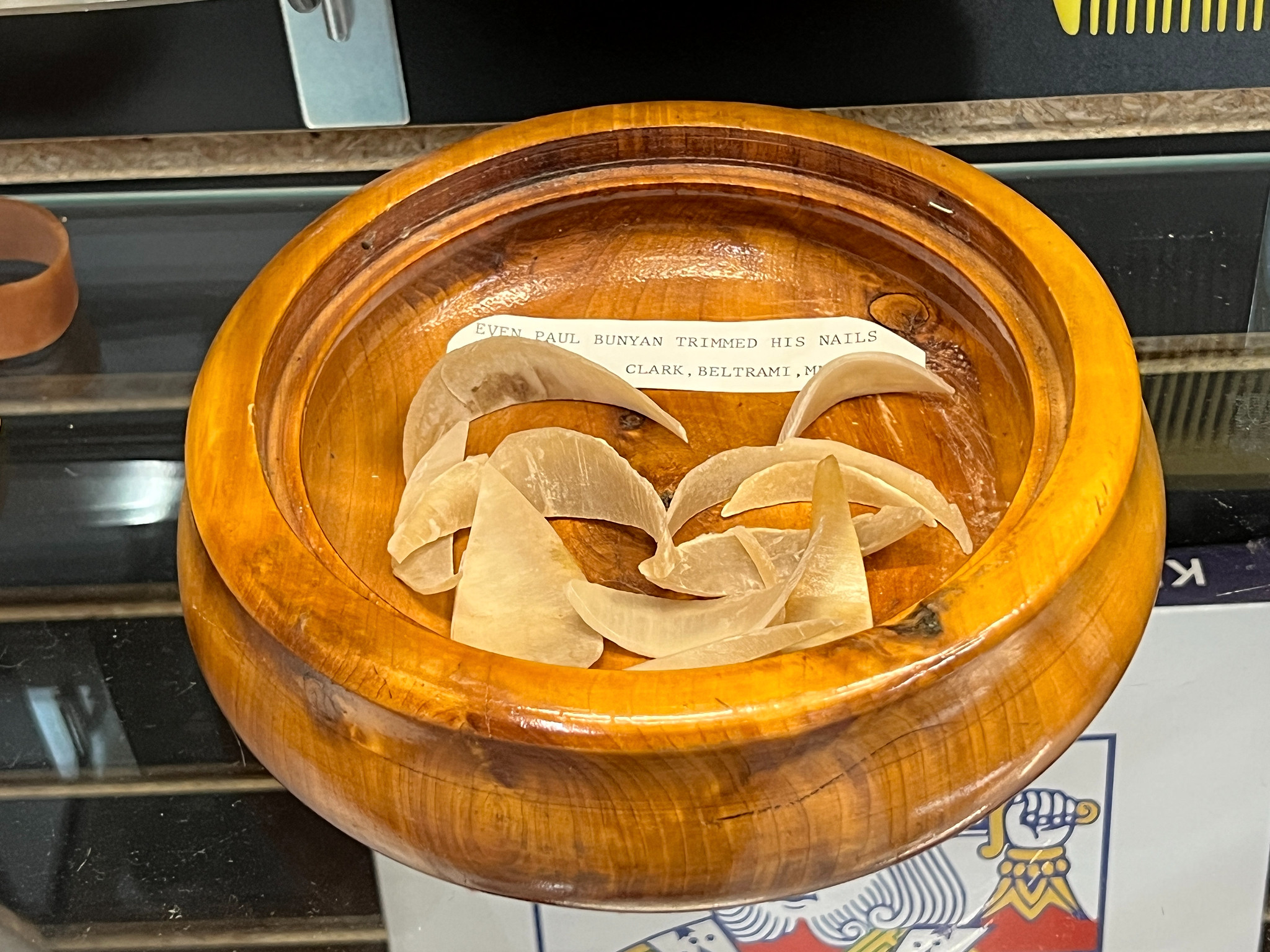 Drevená miska s veľkými nechtami na výstave, doplnená štítkom s menom Paula Bunyana, ústrednej postavy v americkom folklóre.