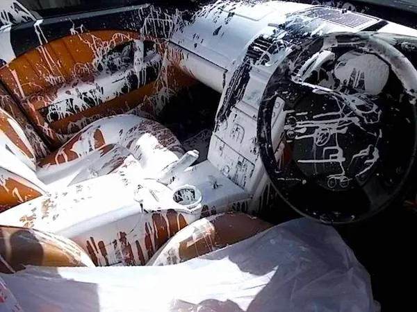 Interiér auta pokrytý bielou farbou, rozliata farba na sedadlách a volante, neporiadok vo vozidle.