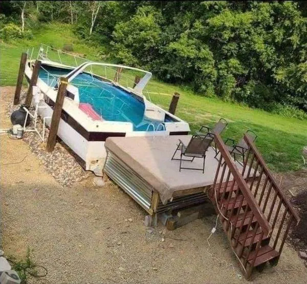 Bazén umiestnený na verande zo starej lode, obklopený prírodným prostredím a dreveným schodiskom.