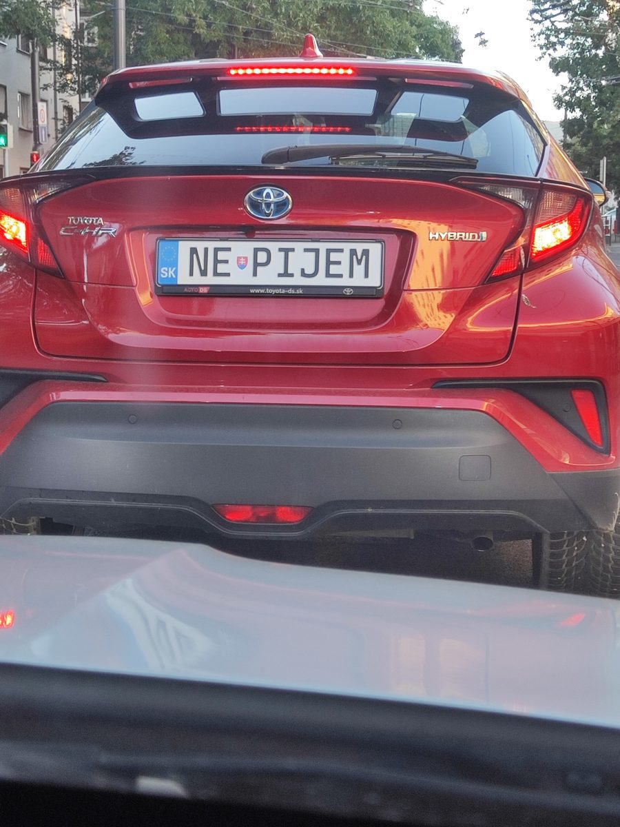 Červené auto Toyota s vtipnou EČV NE PIJEM na ulici Bratislavy.