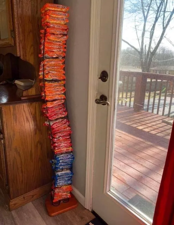 Veža z balení instantných rezancov pri dverách, roztriedené podľa farby obalov.