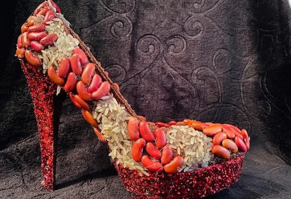 Trblietavá topánka na opätku ozdobená červenými fazuľami a ryžou pre netradičný dizajn.