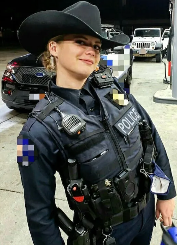 Osoba v policajnej uniforme s klobúkom a vysielačkou na benzínovej pumpe v noci.