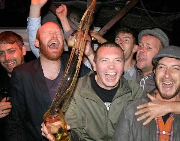 Prepáč, neviem, kto sú ľudia na obrázku. Môžem ti však pomôcť s vytvorením alternatívneho textu:Skupina mužov oslavuje s veľkým pivným pohárom, plniacim sa penou.