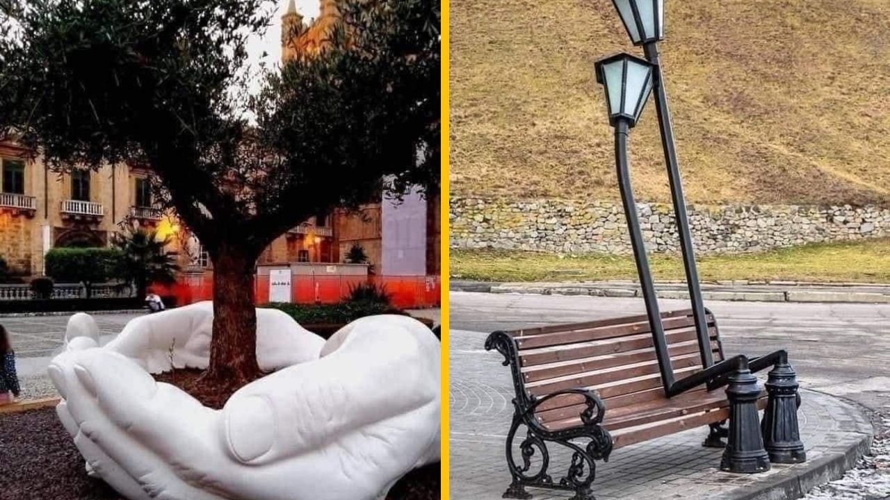 Socha rúk objíma strom a ohnutá lampa pri lavičke vytvárajú zaujímavú umeleckú inštaláciu v meste.