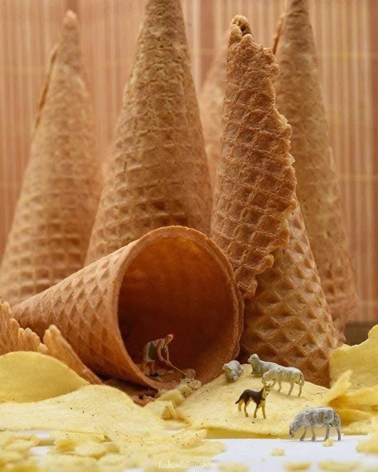 Miniatúrni pastieri so zvieratami blízko obrovských zmrzlinových kornútov a lupienkov vytvárajú surrealistickú scénu.