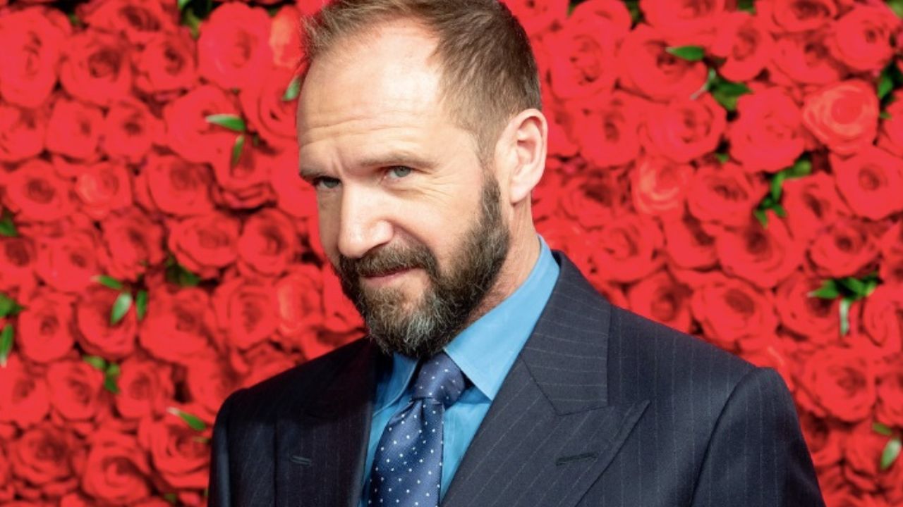 Neznámy muž v obleku pred červenou stenou z ruží, elegancia na červenom koberci.