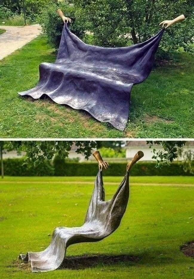 Socha zobrazujúca lavičku držanú rukami, evokuje ilúziu zavesenej deky vo verejnom parku.