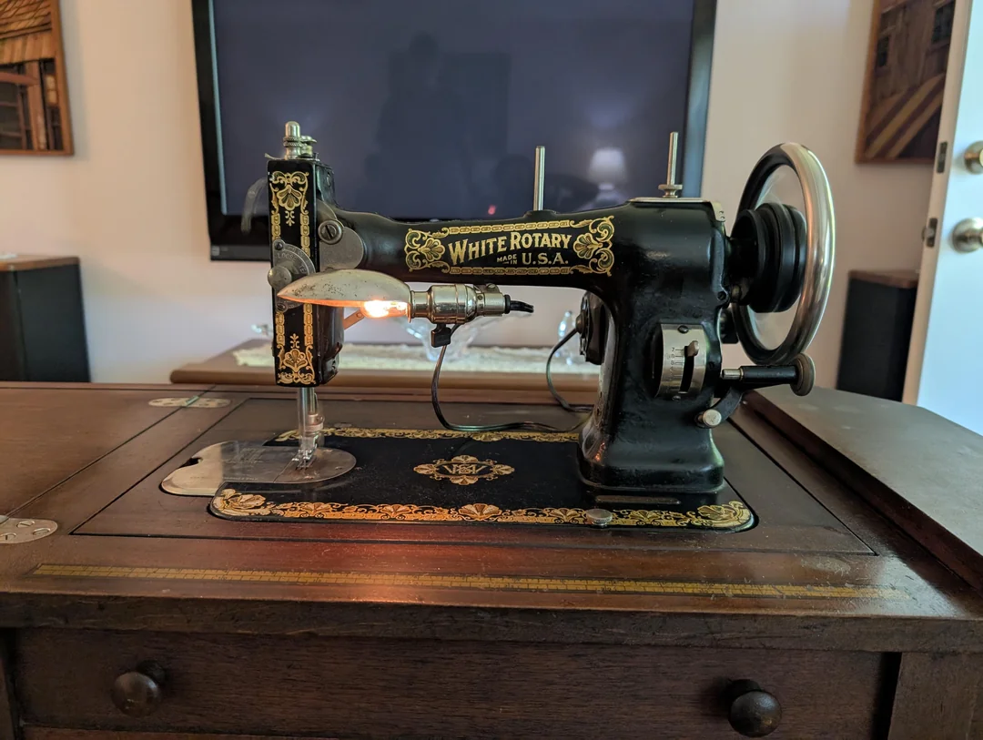 Starý šijací stroj White Rotary na drevenom stole s dekoračnými vzormi, retro dizajn.