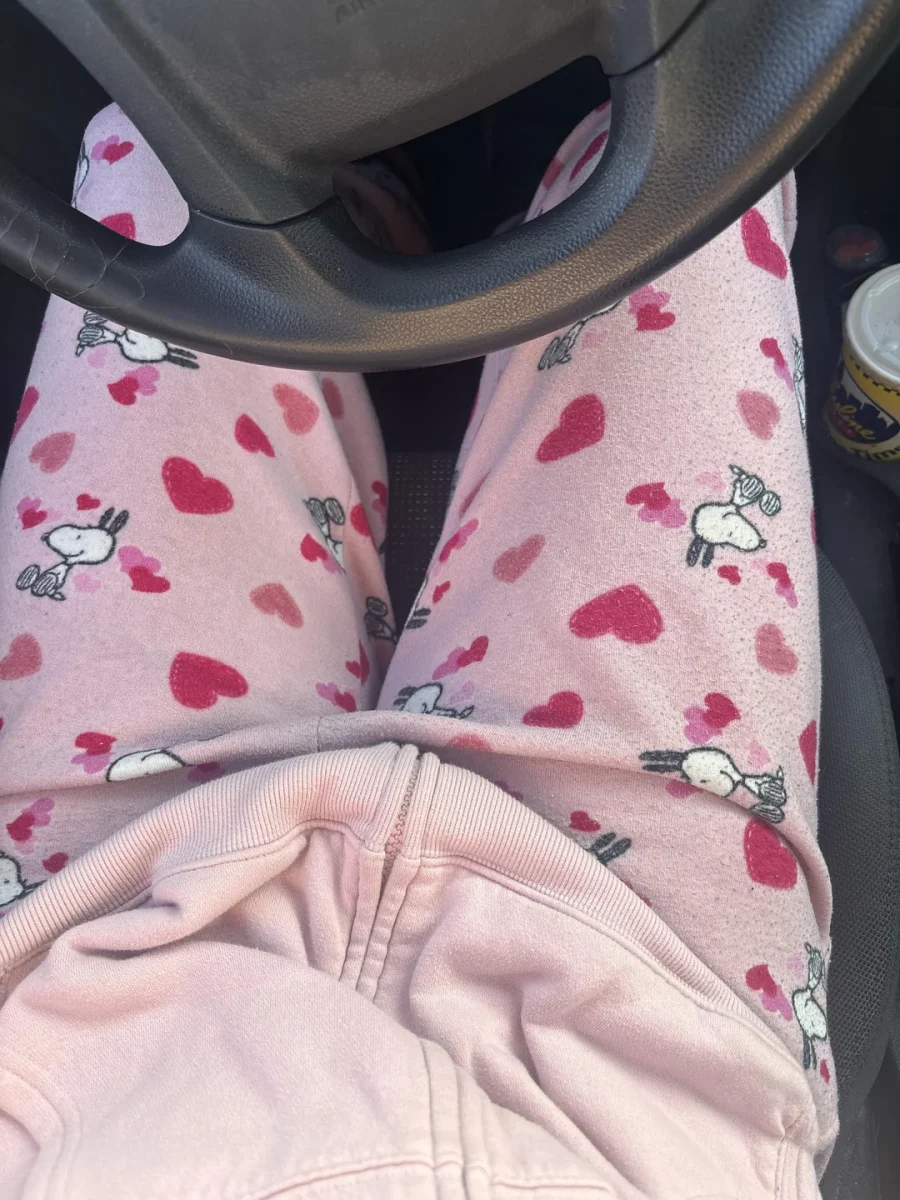 Osoba v aute s ružovými nohavicami so vzorom srdiečok a postavičiek.