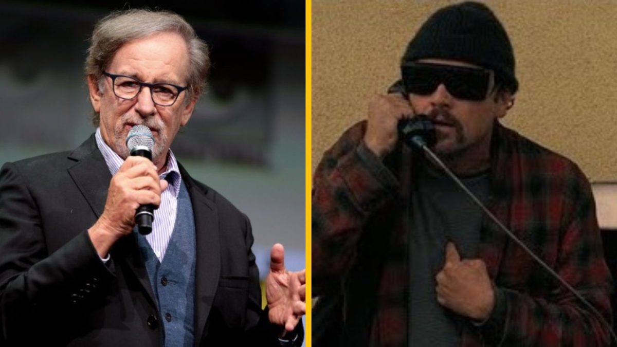 Ľudia rozprávajúci do mikrofónu a telefónu, jeden v obleku, druhý v čiapke a okuliaroch.