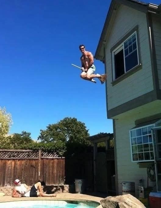 Muž skáče z okna domu na metlu s bazénom a ďalším človekom v pozadí. Letná zábava na dvore.