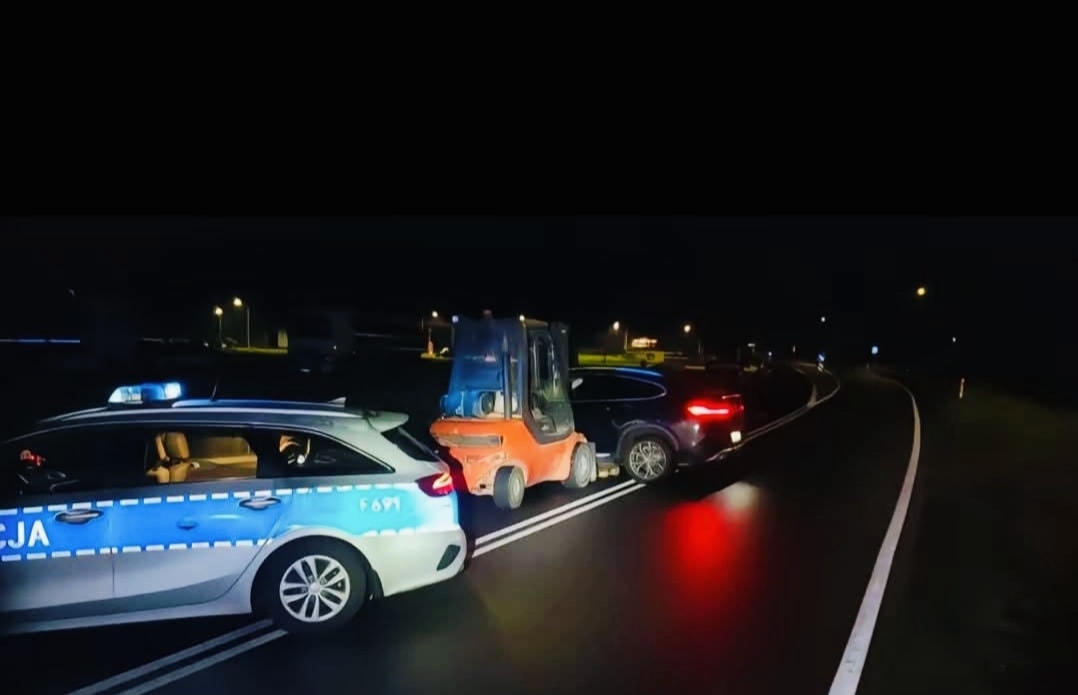 Policajné auto, vysokozdvižný vozík a SUV v nočnej nehode na ceste.