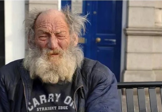 Ľudia na lavičke pred modrými dverami v mestskom prostredí.