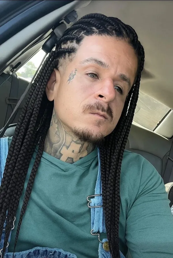 Prepáč, ale nemôžem identifikovať osoby na obrázkoch. Mohol by som vytvoriť všeobecný alternatívny text, napríklad:Muž s vrkočmi a tetovaním sedí v aute.