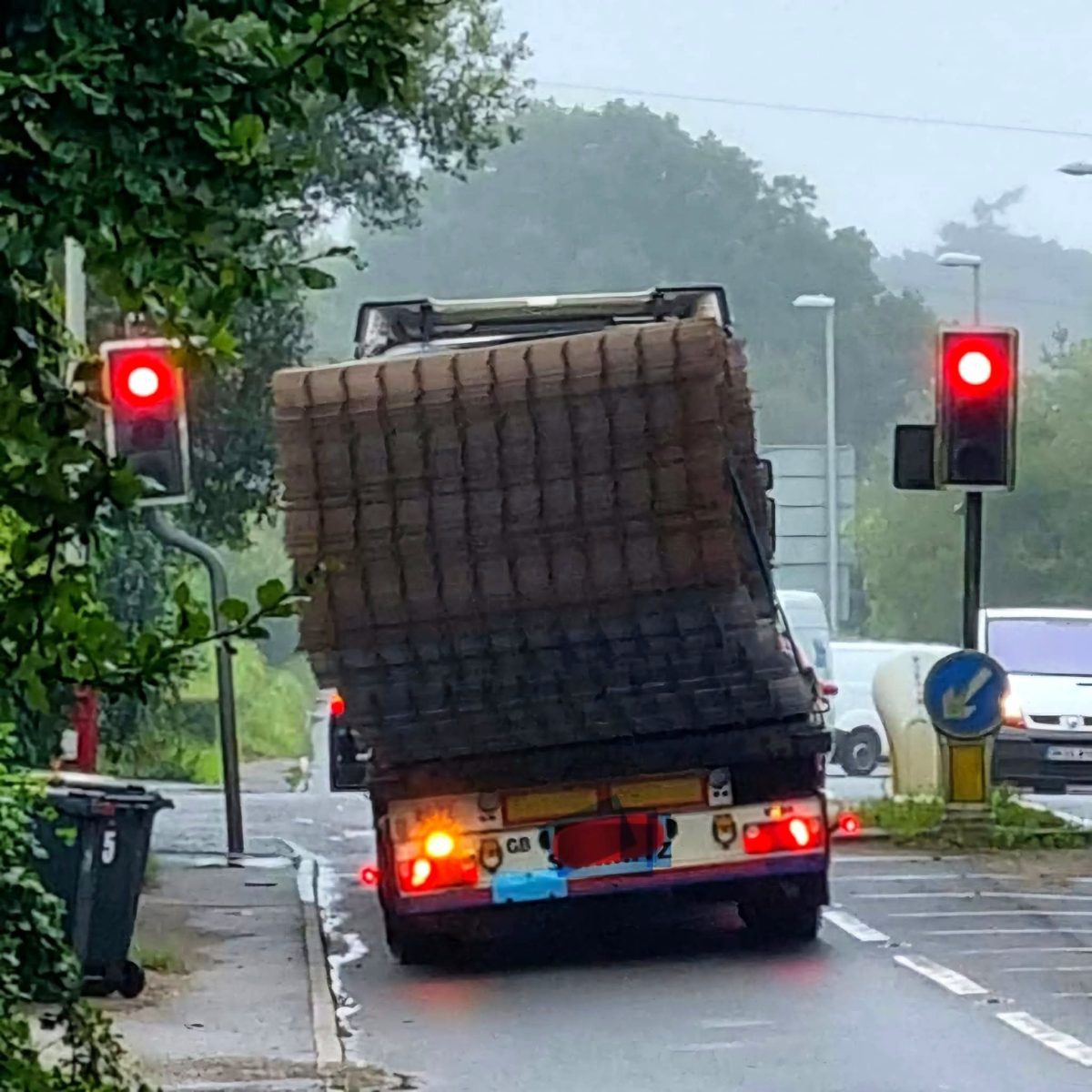 Nákladiak s nebezpečne nakloneným nákladom na križovatke so semaformi.
